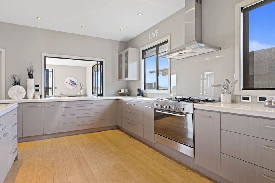 A generously designed open-plan kitchen, elegantly equipped with an oven, fridge, freezer, dishwasher, and a complete set of kitchen utensils and cutlery.