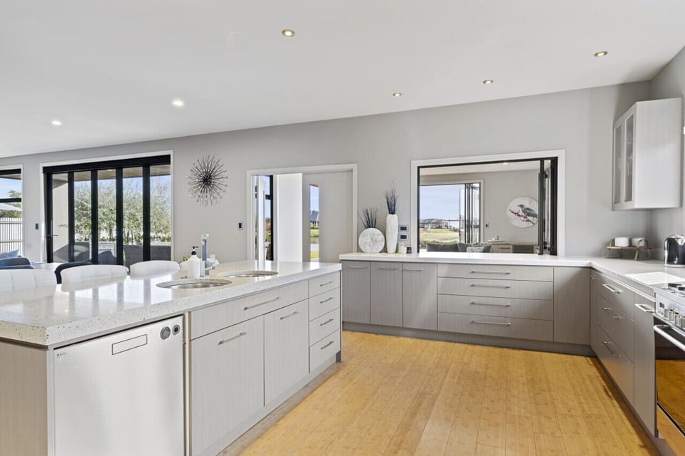 A generously designed open-plan kitchen, elegantly equipped with an oven, fridge, freezer, dishwasher, and a complete set of kitchen utensils and cutlery.