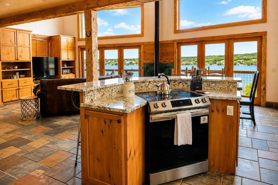 Open-concept kitchen and living area with granite countertops, stainless steel appliances, soaring windows, and beautiful Lake Travis views.