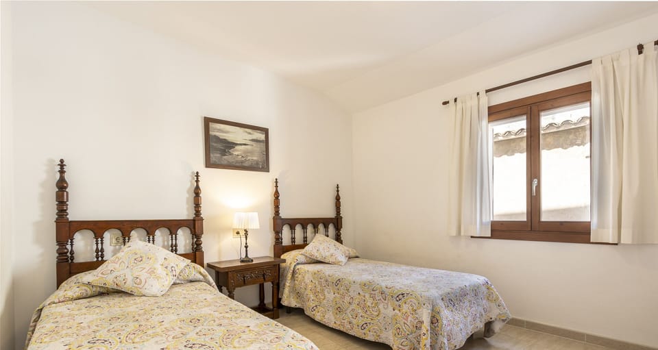 Twin bedroom with traditional Mallorcan decor, natural light and exterior window.