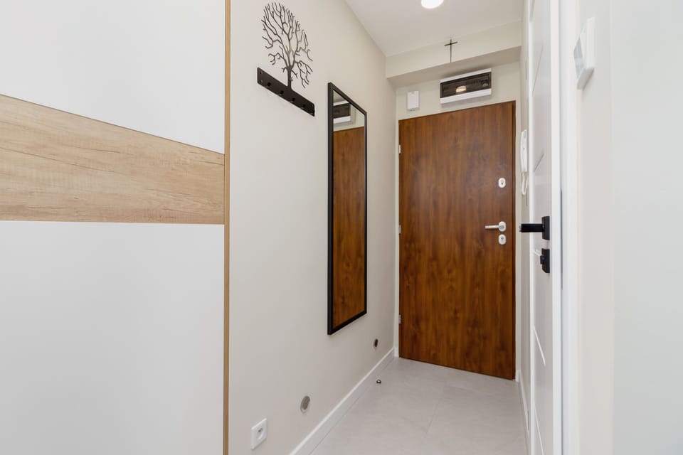The apartment entrance with wooden doors, a stylish tree graphic on the wall, and a large mirror.
