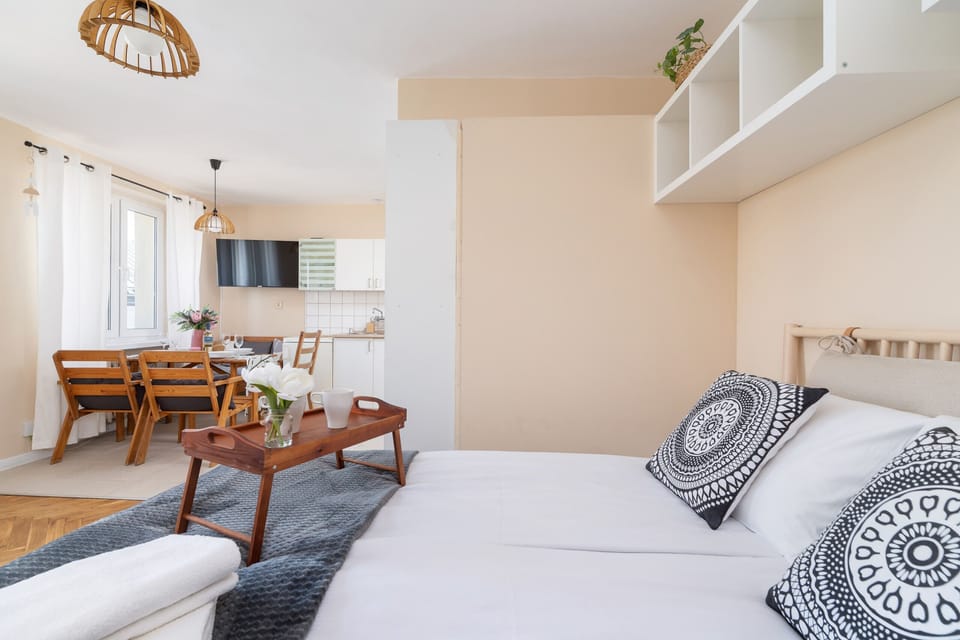 A cozy bed with decorative pillows and shelves for storage above it.
