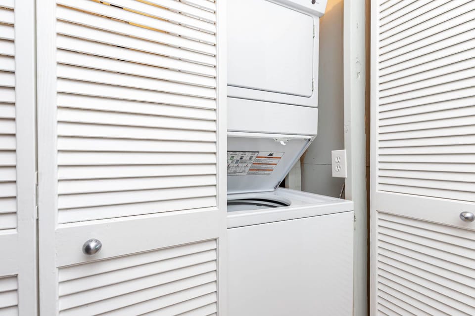 This laundry area features a convenient stacked washer and dryer behind stylish louvered doors for easy access
