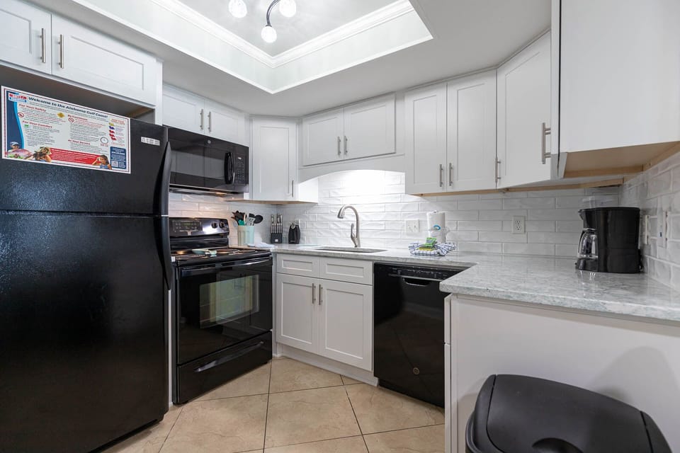 This kitchen features sleek black appliances, granite countertops, and a coffee maker for your convenience
