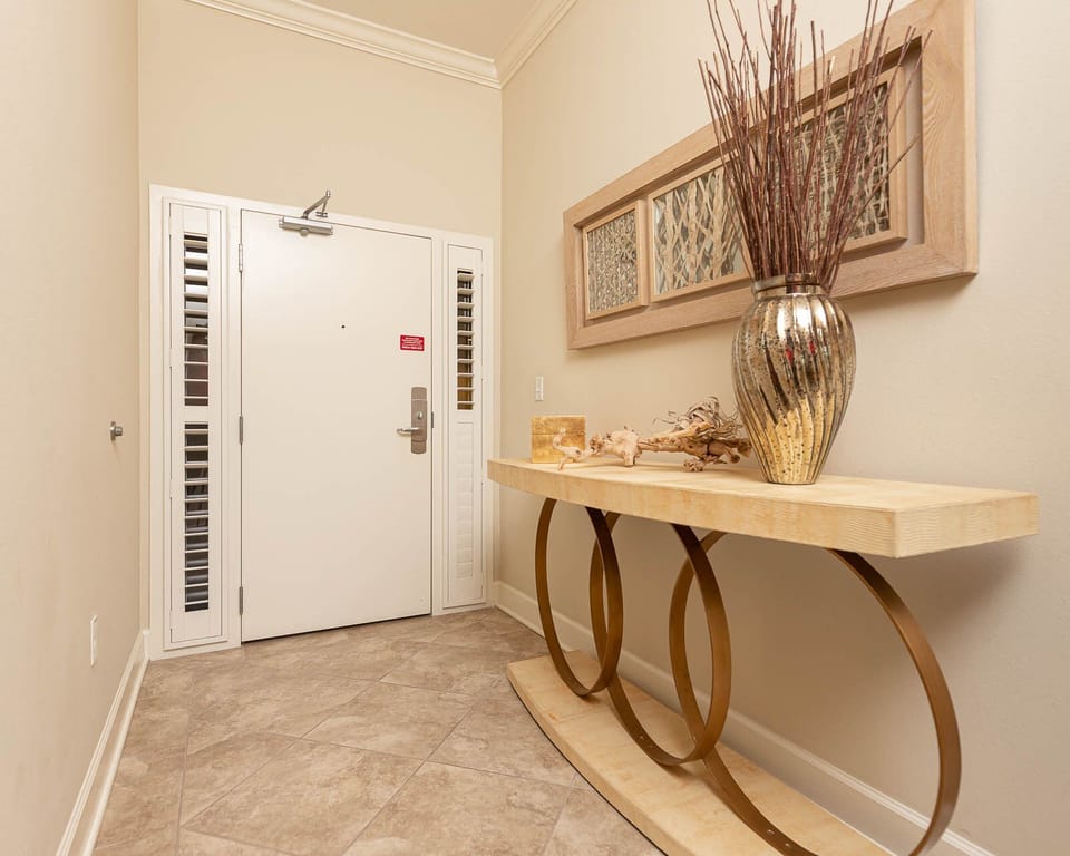 The entryway features a stylish console table with a metallic vase and decorative accents, setting a warm tone for your stay
