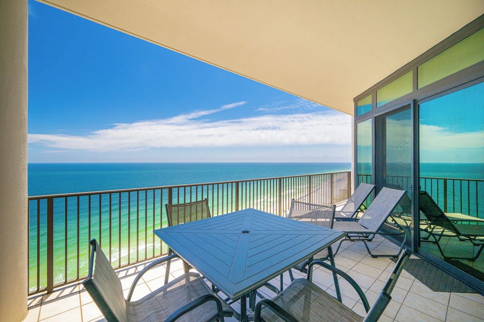 This balcony features a table and chairs for dining, offering stunning views of the beach from the twenty-first floor