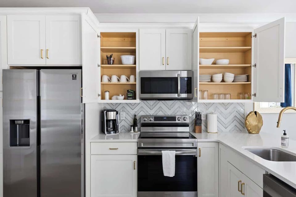 Kitchen fully stocked with plates, bowls, cups, wine glasses, utensils, cooking tools, pots, pans, baking sheets, blender, toaster, mixer, coffee, creamer, sugar, drip coffee pot, filters, oil, salt, pepper