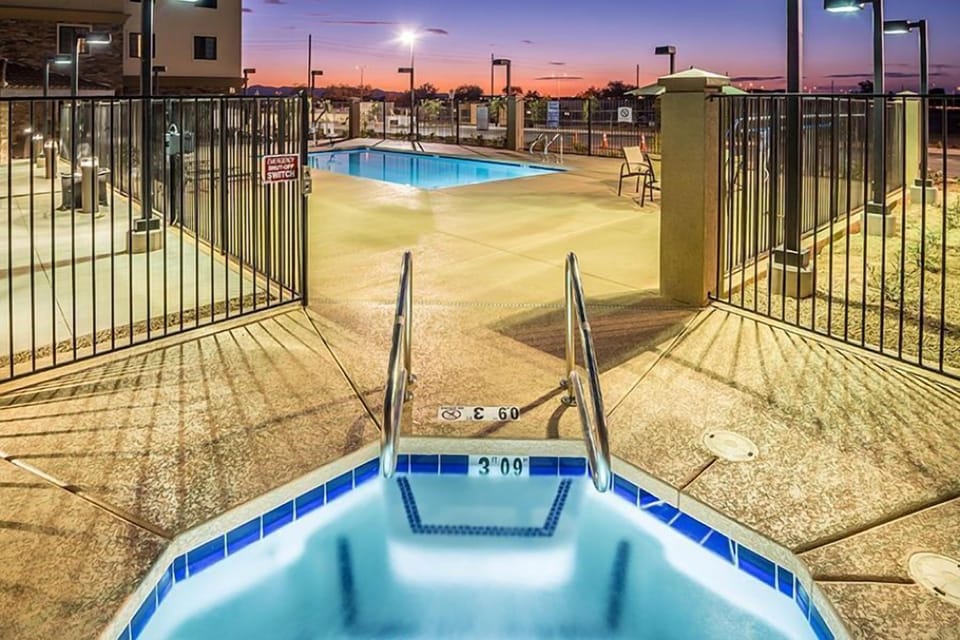Outdoor pool at sunset with surrounding fencing and deck area.