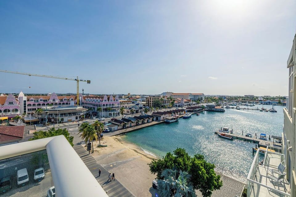 Stunning harbor panorama showcases colorful waterfront buildings, crystal-clear turquoise waters, and bustling marina activity under brilliant Caribbean skies.
