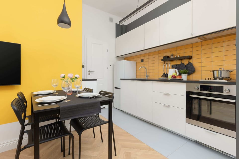 A kitchen view featuring appliances, a yellow wall, and white cabinets.
