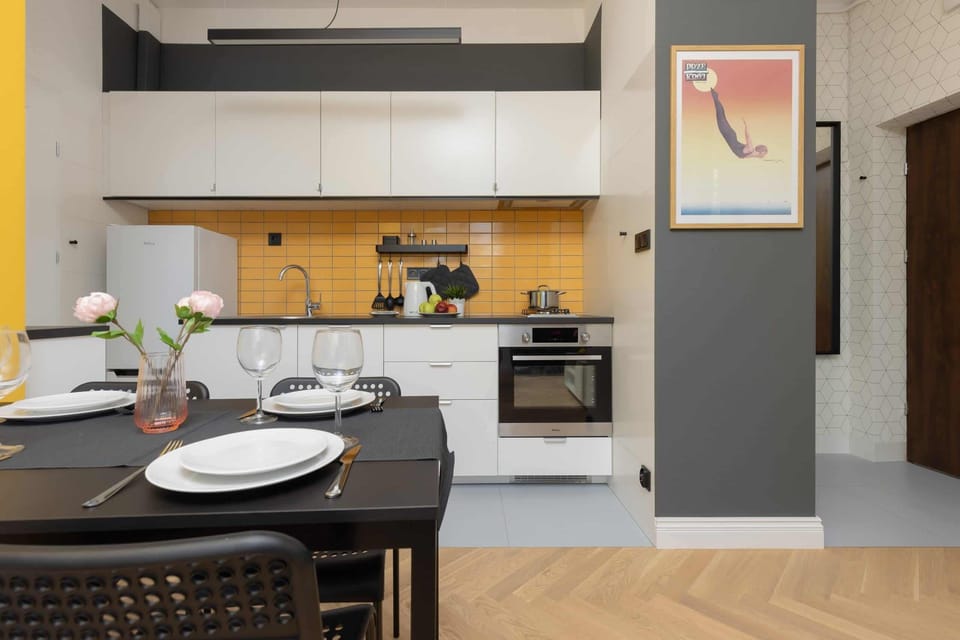 A kitchen with white cabinets and a yellow backsplash in a modern style.
