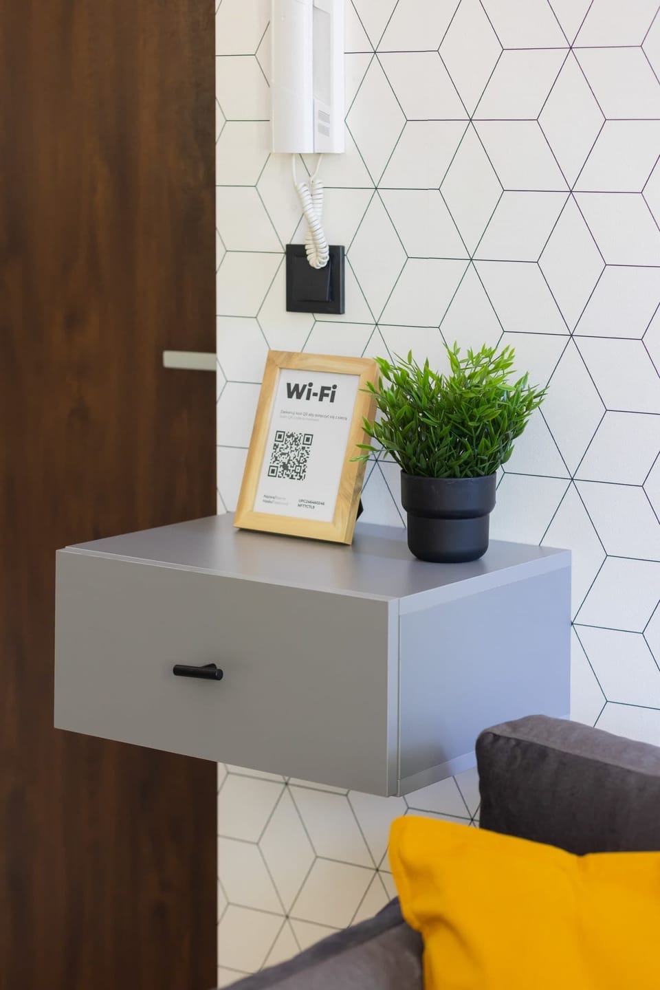 A small gray wall-mounted shelf, styled with a framed photo and a plant pot for a minimalist aesthetic.
