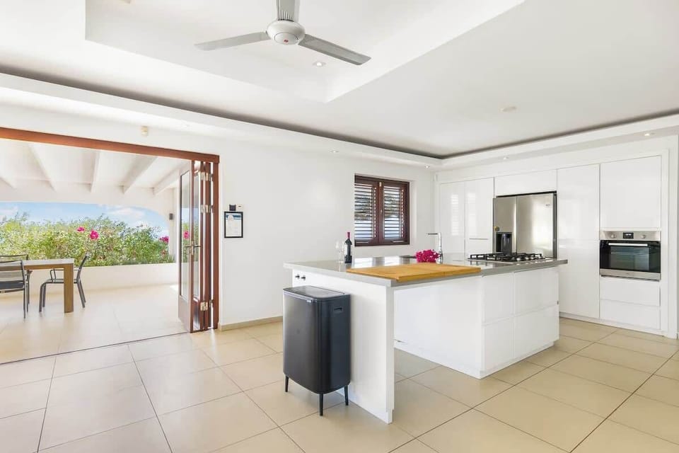 Bright and spacious kitchen with bar seating and direct access to the terrace — ideal for social cooking and easy outdoor dining.

