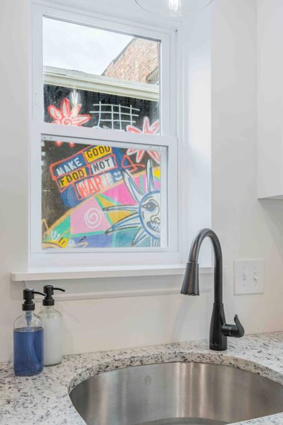 Feast your eyes on the vibrant wall mural just beyond the kitchen window, infusing inspiration and creativity into every meal.