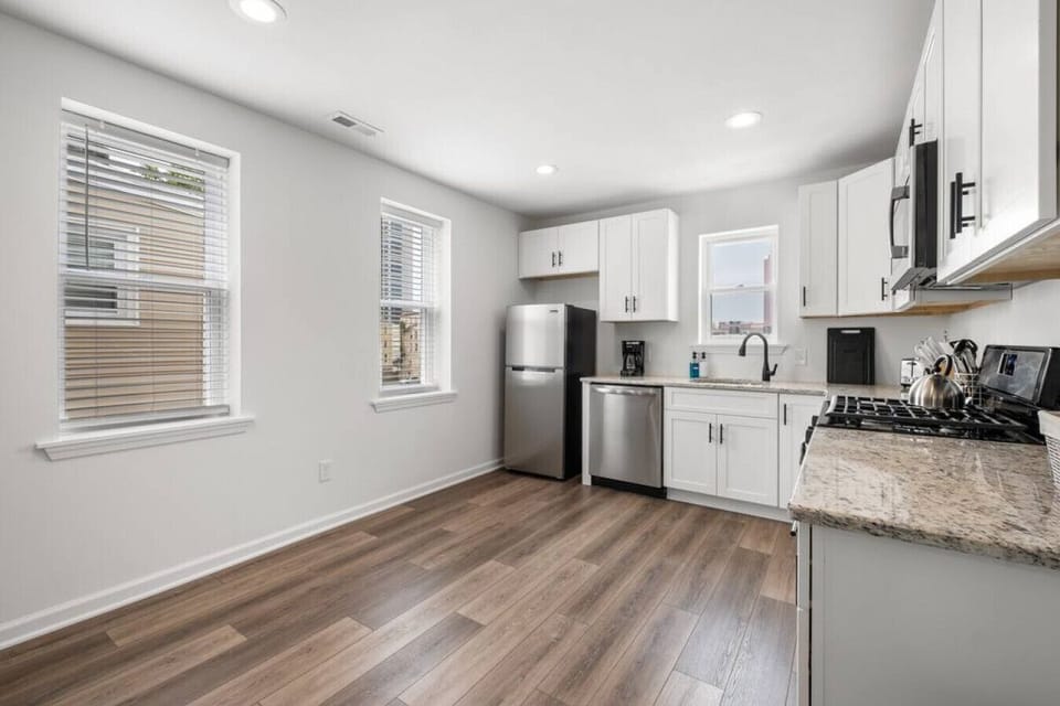 Modern and sunlit, this kitchen features sleek white cabinets, and stainless steel appliances, perfect for enjoying meals in style.