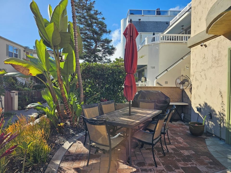 Patio table w/ seating for 6 & an umbrella. Note the Stainless Steel Grill!