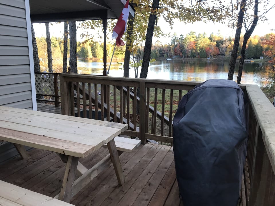 BBQ and picnic table on deck with a view of the lake