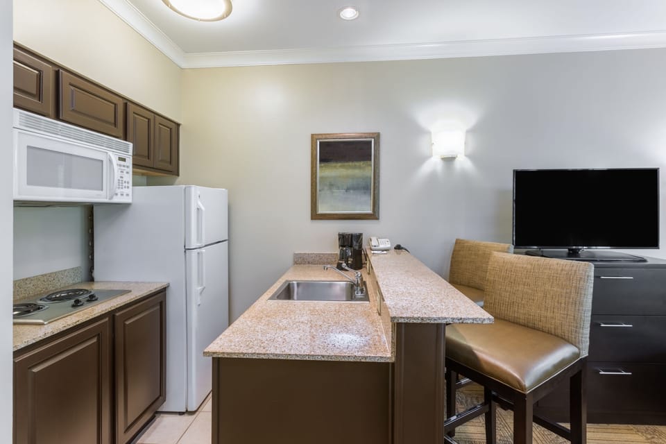 Fully equipped kitchen with refrigerator, microwave, cooktop, and ample counter space.