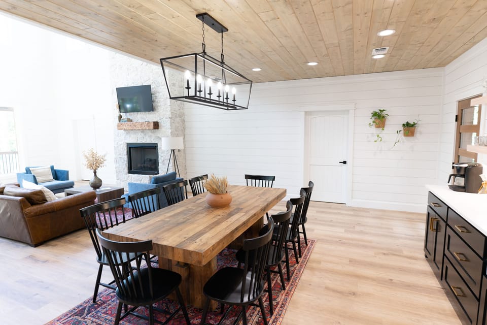 A fully stocked eat in kitchen with modern appliances and a sink that overlooks the trees through the back deck