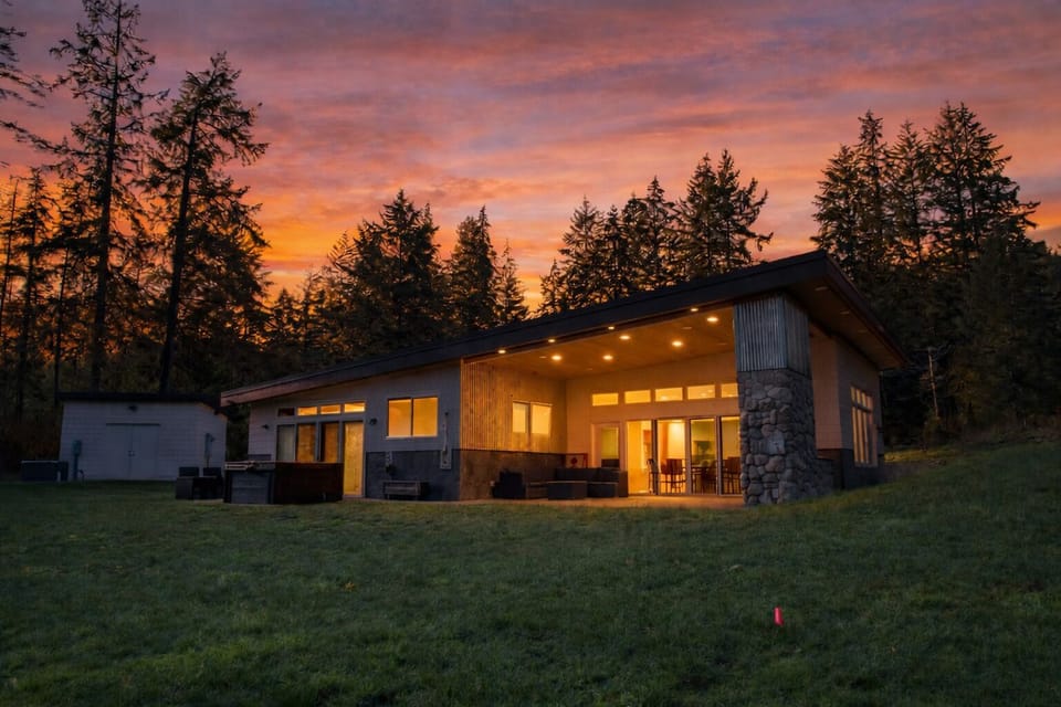 Modern water view home with covered patio and glowing evening ambiance