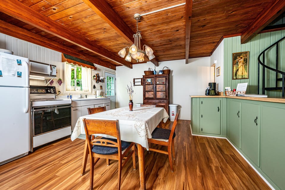 Dining area with wooden table and chairs beneath a wood-beamed ceiling and vintage chandelier.