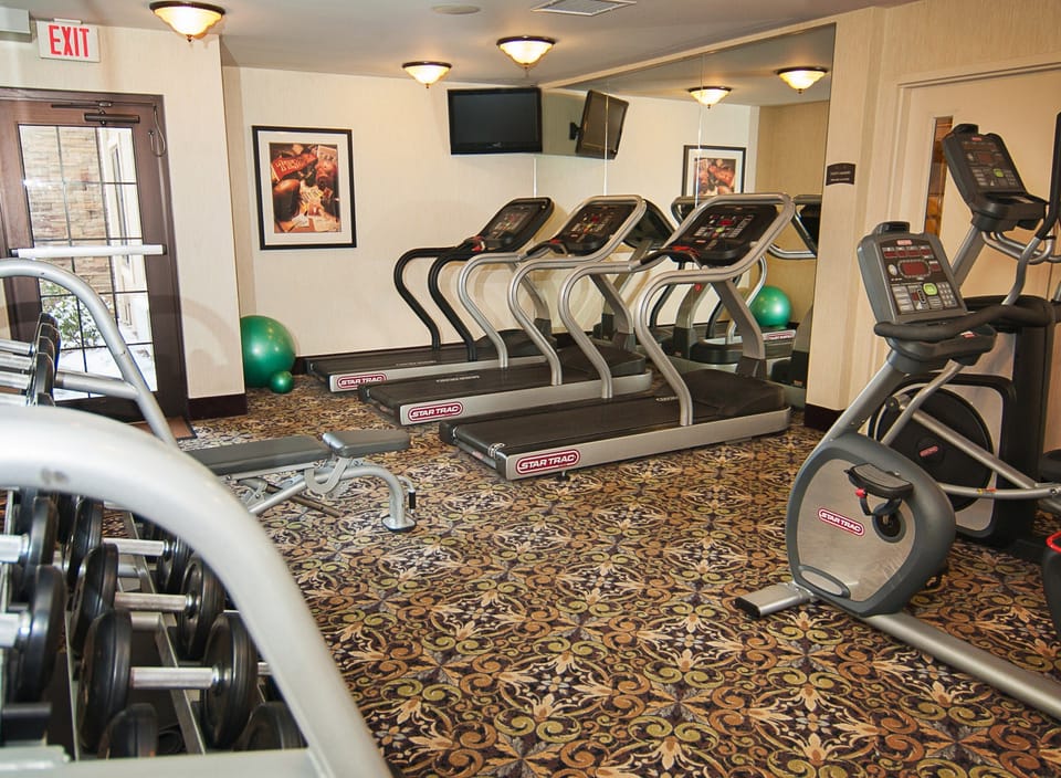 Fitness center with treadmills, stationary bikes, and free weights, open 8am to 8pm daily