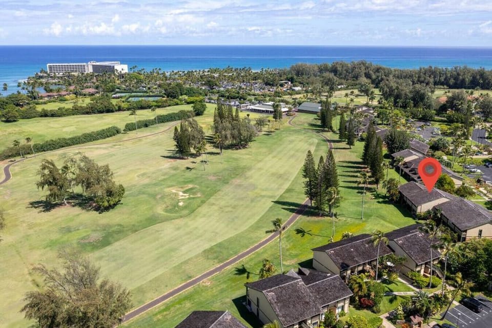 Golf-course greenery stretching toward the ocean from above