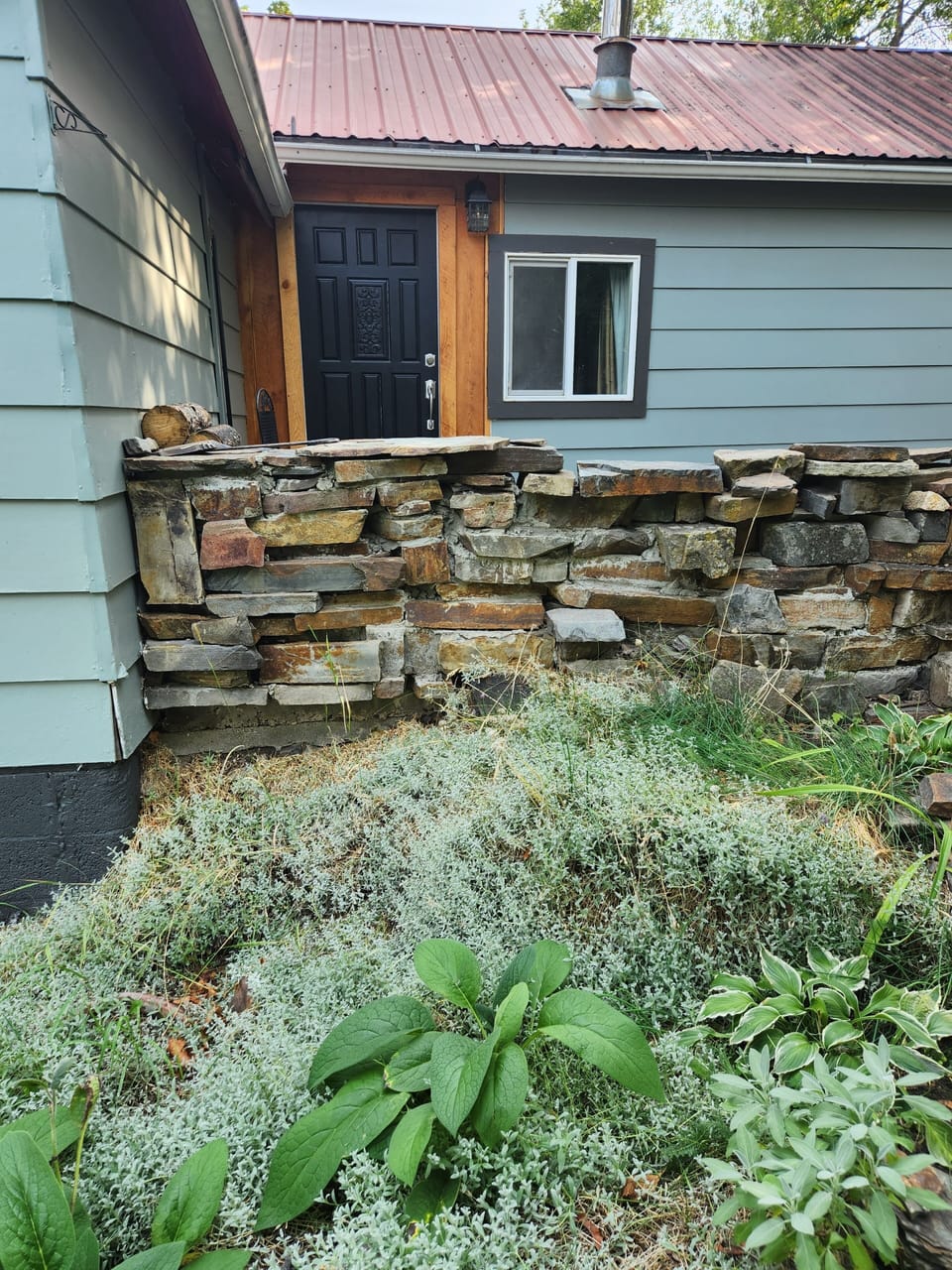 Front door, with a chair, some wood, and a small Bar-B-Q,  with charcoal. 