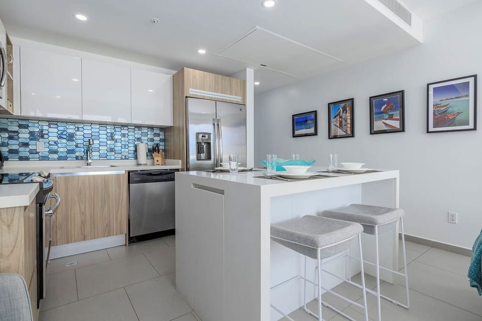 Your modern kitchen features sleek appliances, vibrant blue tile backsplash, and a breakfast bar—perfect for preparing meals and casual dining during your stay.