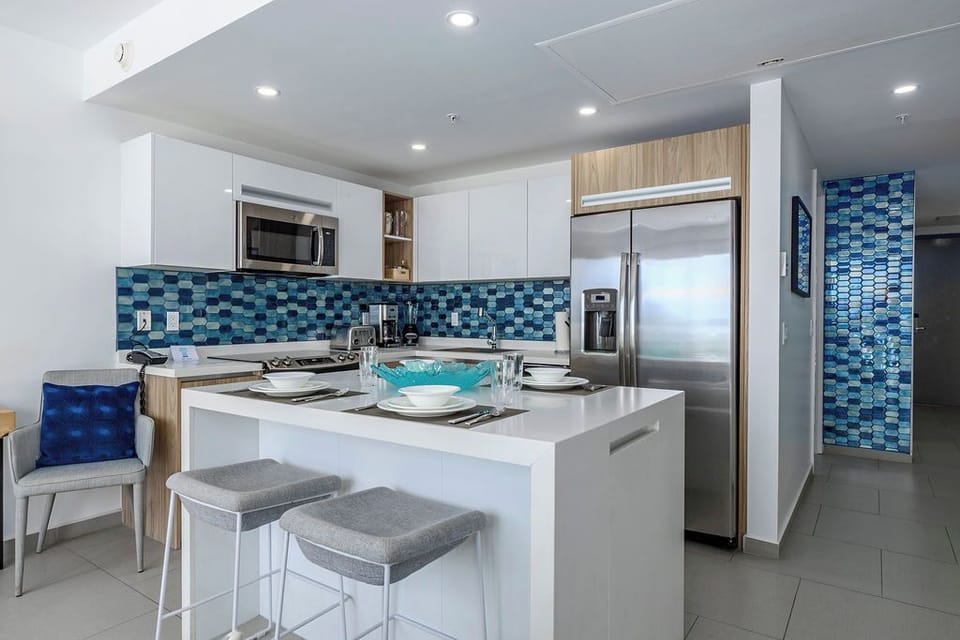 Sleek white cabinets, vibrant blue mosaic backsplash, and modern stainless steel appliances await you in this stylish open kitchen. The island offers casual seating—perfect for morning coffee or evening cocktails.