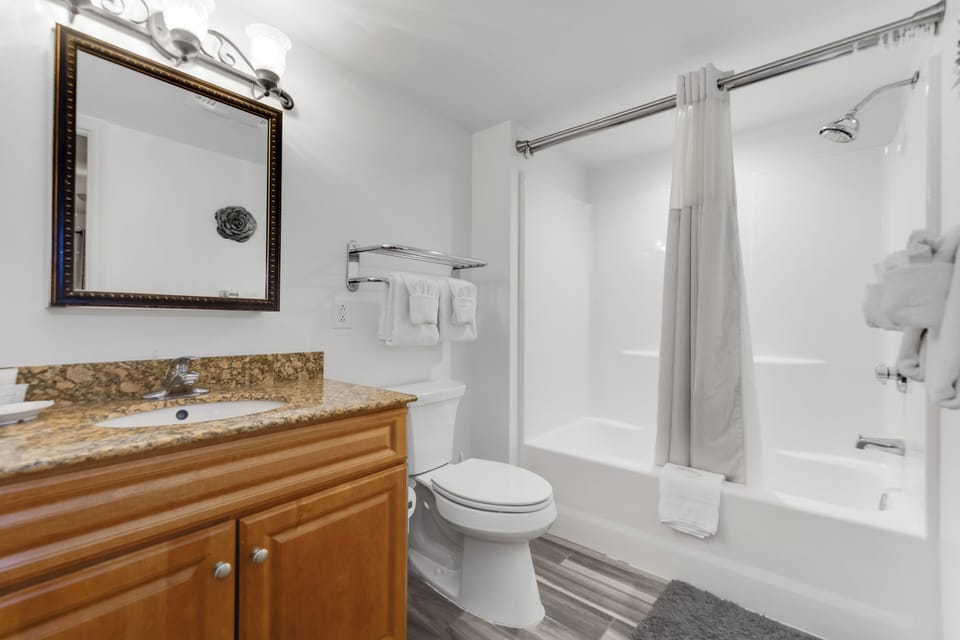 Step into your private bathroom featuring a granite vanity, soaking tub with shower, and plush towels awaiting your arrival.