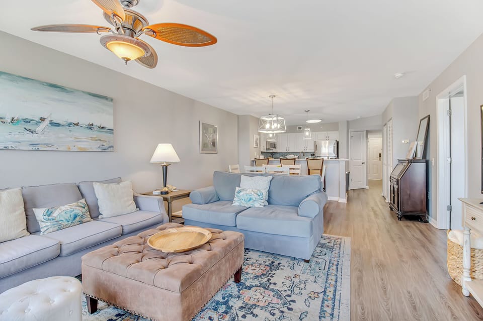Unwind in your spacious living area with soft blue sofas and tropical ceiling fan that creates the perfect coastal breeze for relaxation.