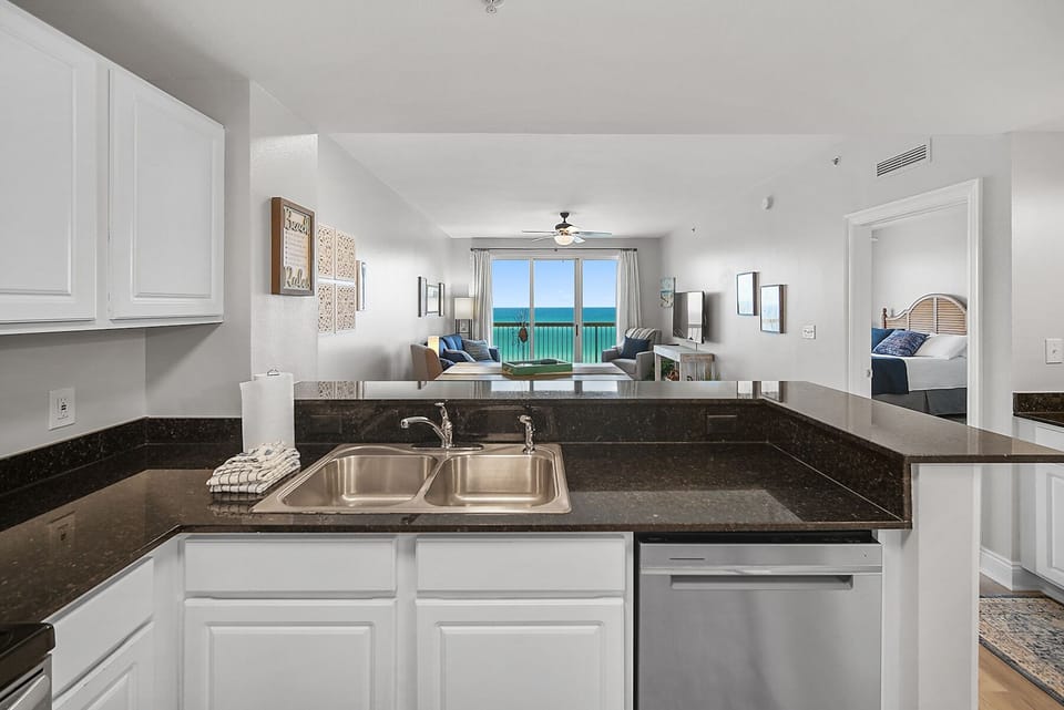 Your open kitchen flows seamlessly into the living area, where stunning ocean views through floor-to-ceiling windows create the perfect backdrop for vacation dining.