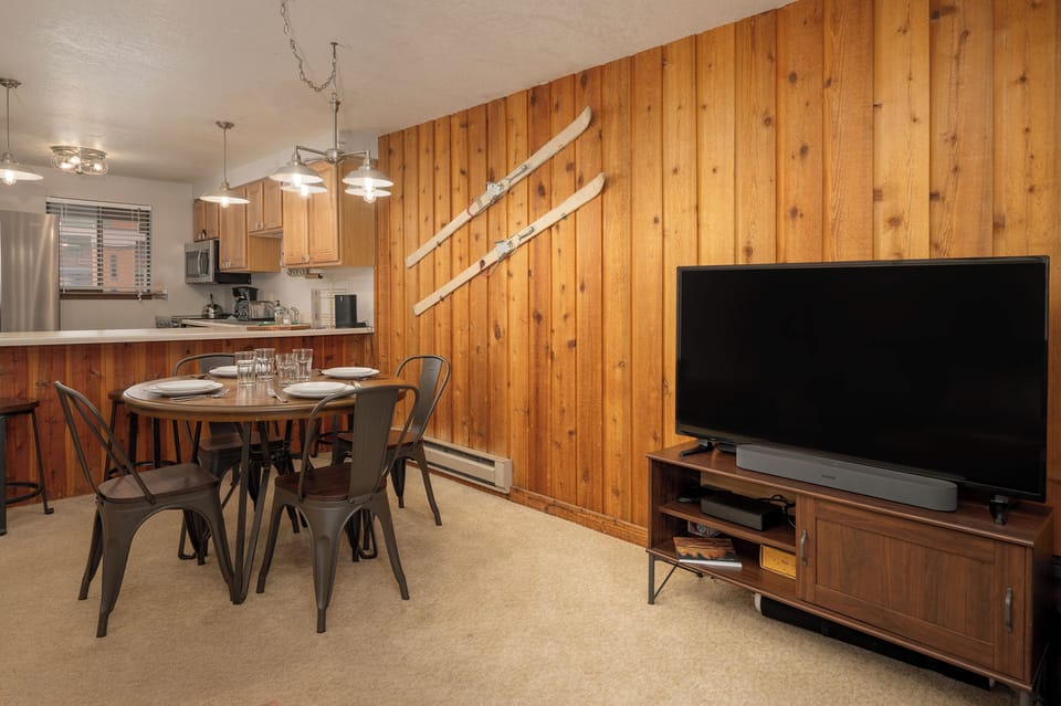 Cozy mountain living awaits with warm wood walls, your dining space, and entertainment center for relaxing evenings.