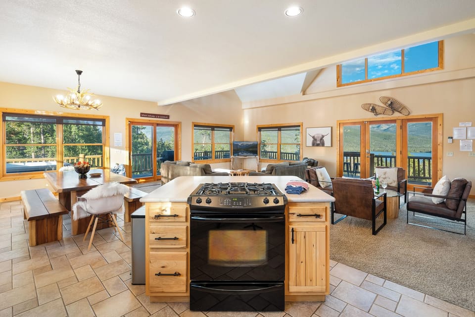 Gather around this open-concept space where floor-to-ceiling windows frame sweeping mountain vistas. Your kitchen flows into cozy living areas—perfect for morning coffee or evening meals with those unforgettable views at every turn.