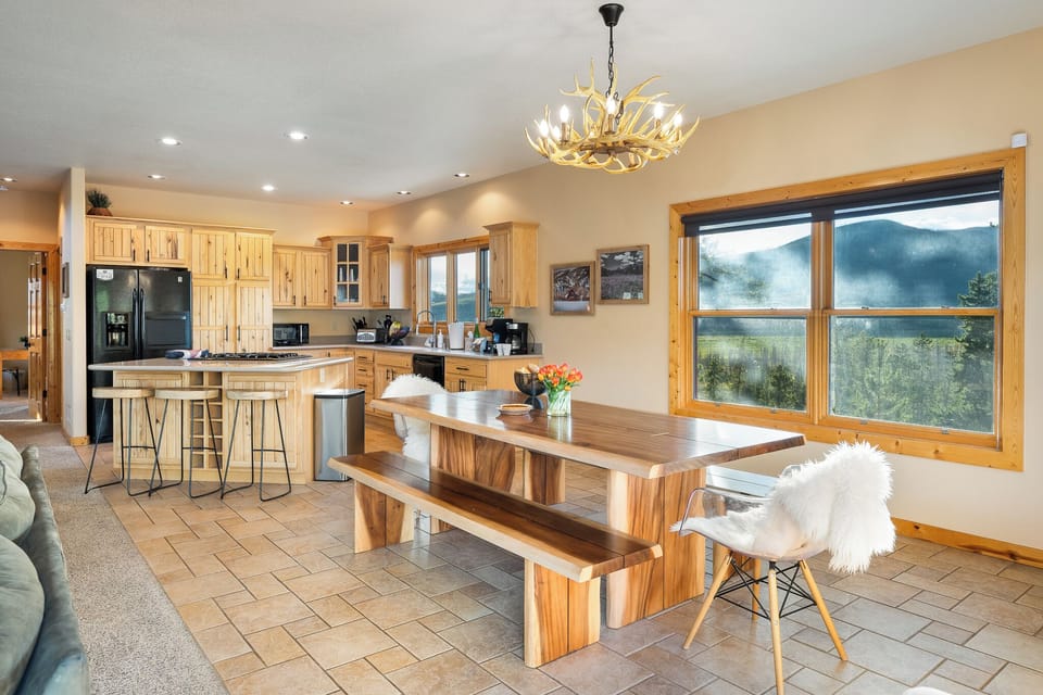 Your bright open kitchen and dining area invites you to gather around the handcrafted wood table with mountain views framing every meal through expansive windows.