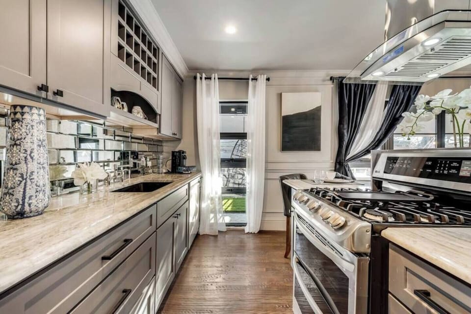 Beautiful gourmet kitchen featuring a sleek gas range and a fully equipped setup for all your cooking needs. The spacious island offers extra prep space and doubles as a casual dining area. With stylish lighting throughout, this kitchen is both functional and inviting, perfect for preparing meals or enjoying a cup of coffee.