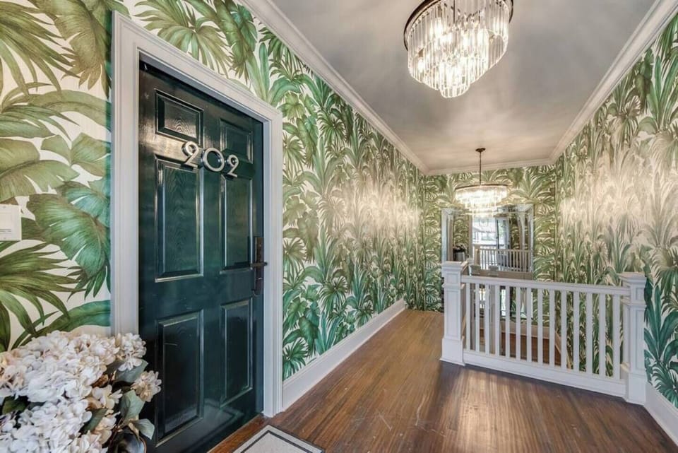The entryway features earthy, patterned wallpaper and a stylish blend of tile and wood flooring. As you step inside, you'll be welcomed by an upscale, inviting atmosphere that sets the tone for a comfortable and elegant stay. Please note, stairs are required to access the unit.
