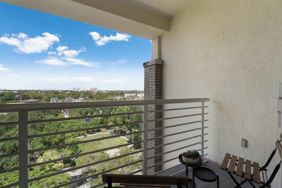 Covered private balcony with bistro seating overlooking lush greenery