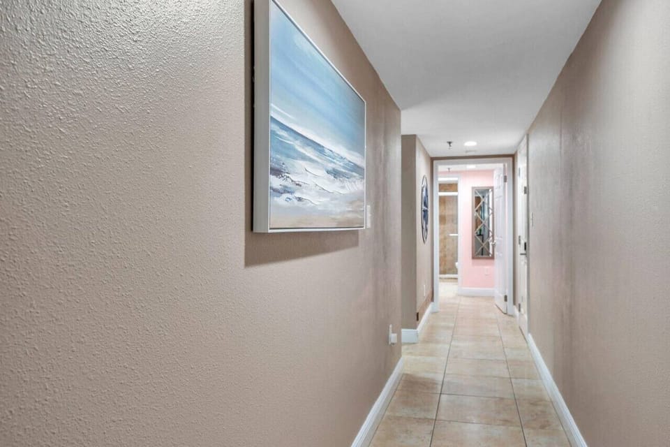 Bright hallway w/ artwork and clean lines, connecting the bedrooms and living spaces.