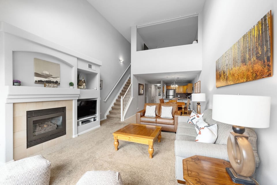Relax in your spacious living room featuring a cozy fireplace, comfortable seating, and modern amenities for the perfect mountain retreat.