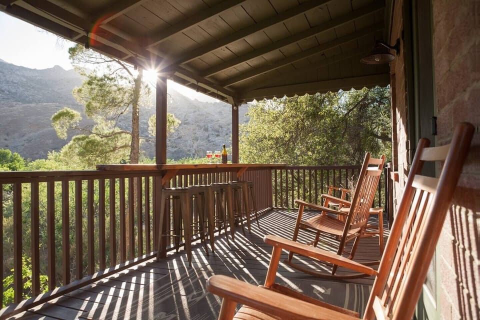 Gated back deck with a view of the Greenhorn Mountains. Rocking chairs & live edge wood bartop with stools complete the scene.