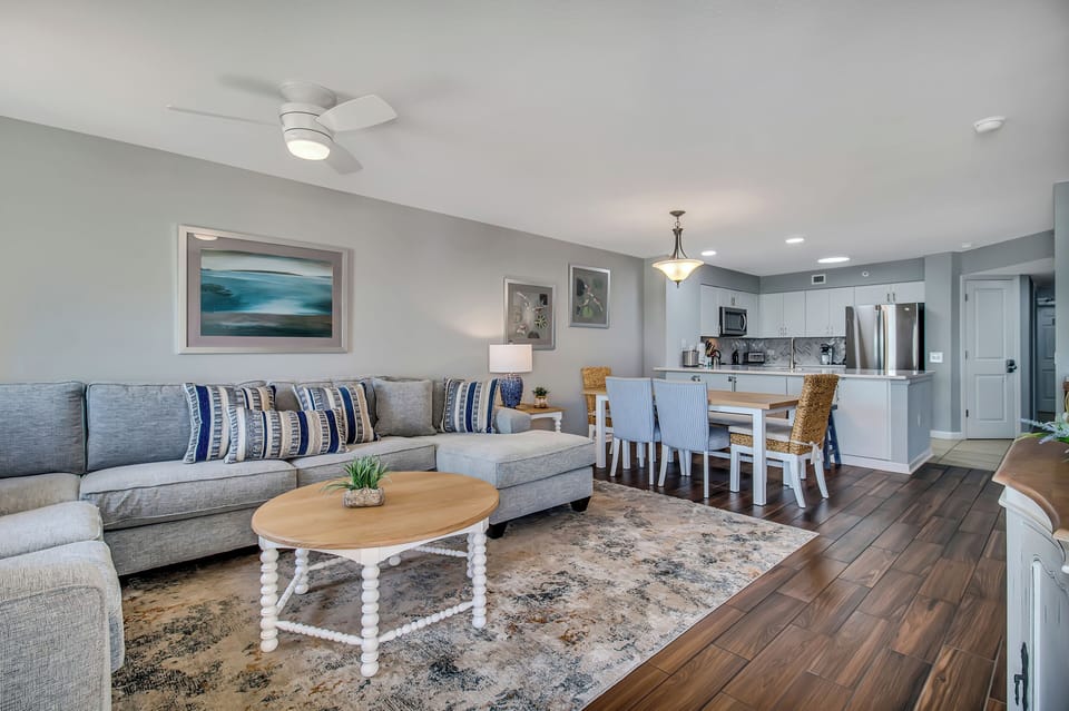 Relax in your spacious open-concept living room with coastal décor, comfortable seating, and a fully equipped kitchen perfect for family meals.