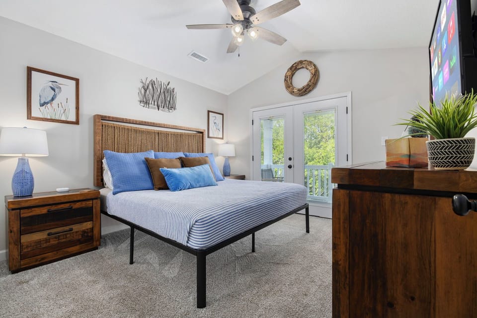 Claim the hand-woven headboard king room for the couple who wants balcony access — French doors open to the upper deck, heron art on the wall, a king bed ready.