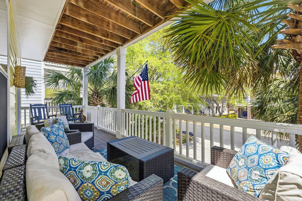 Step out to the balcony and claim your spot on the outdoor furniture — white railing, palm trees below, and the kind of view that makes coffee taste better.