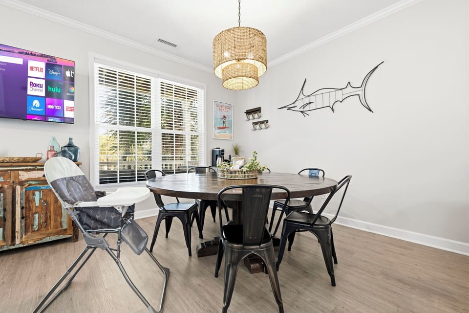  Seat the whole crew at the round dining table for a real group dinner — wicker pendant light above, marlin on the wall, smart TV if sports is on.