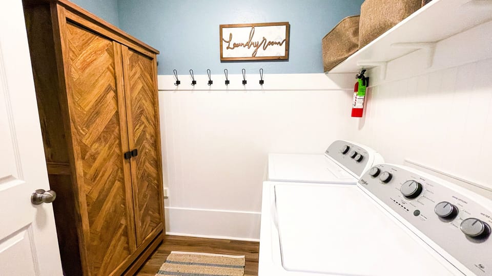 Laundry room includes a game cabinet and extra folding chairs and tray tables
