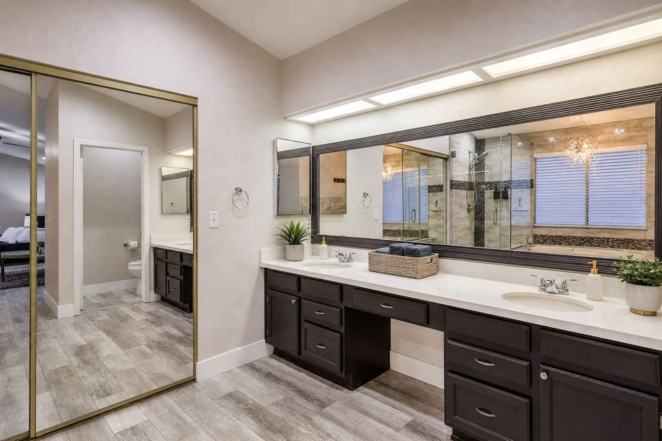 Spacious primary bath: double sinks, bright lighting, walk-in shower