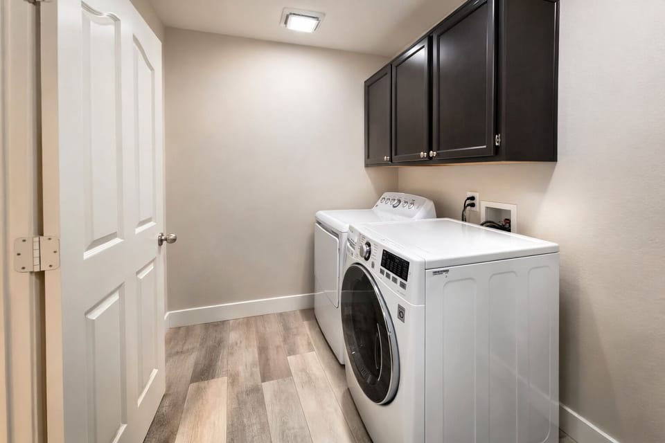 Modern laundry room with full-size washer/dryer and ample cabinet storage
