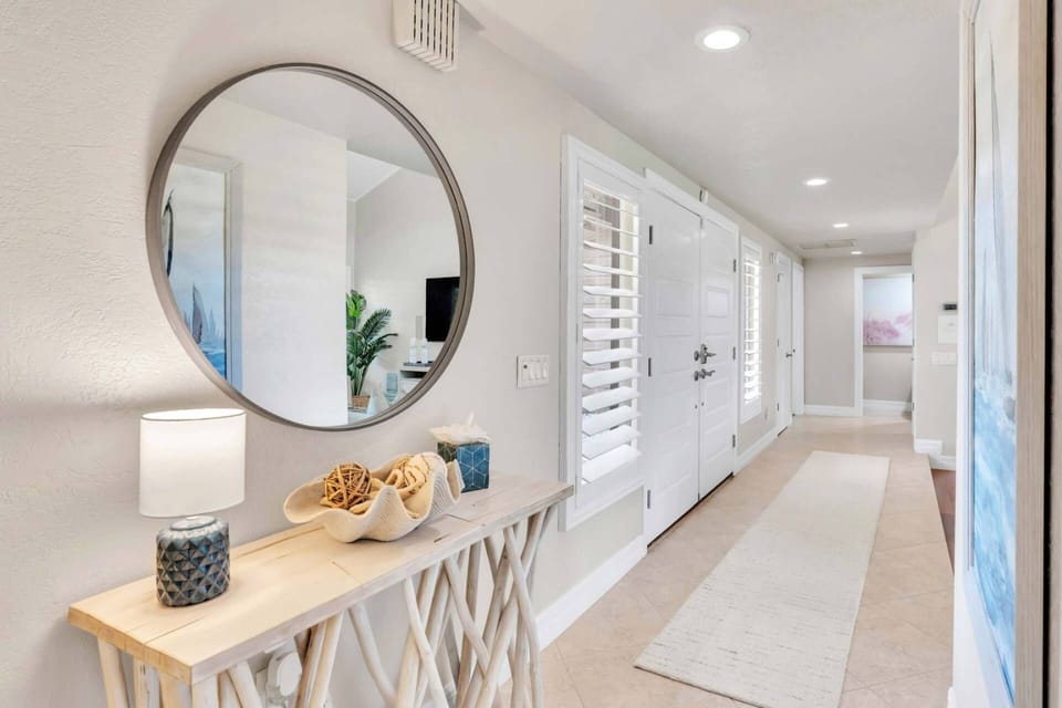 The hallway features a large mirror and a wooden furniture to spice up the space